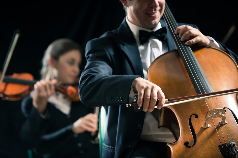 cellist performing joyfully in an orchestra